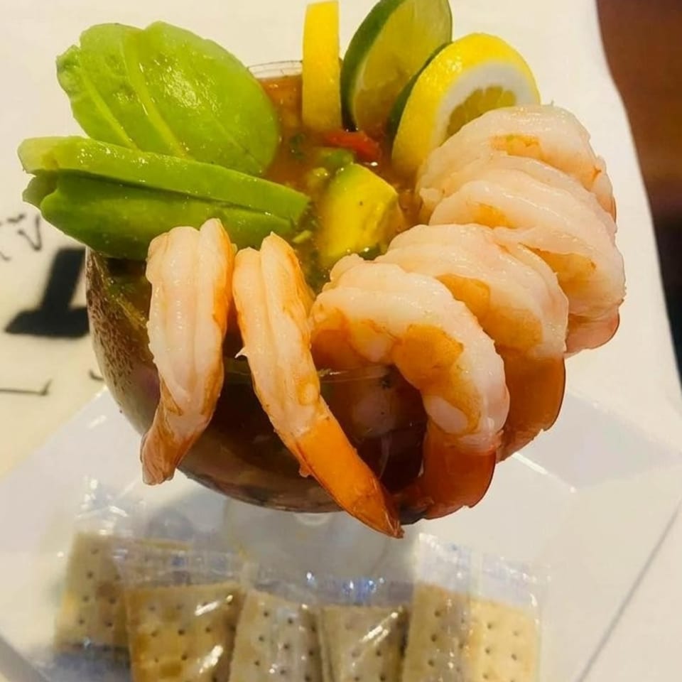 Shrimp cocktail with avocado, lime, and lemon slices, served with crackers at La Barra Del Taco.